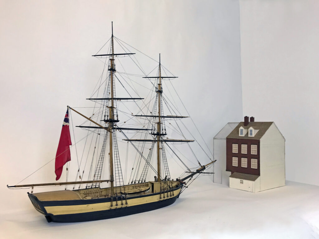 Model of the four story Captain Rose House next to model of a two-masted sailing vessel.