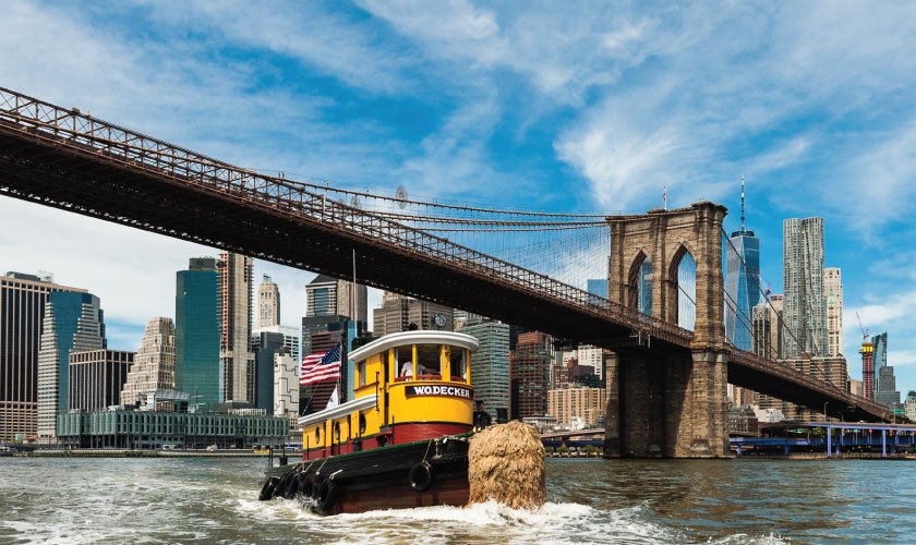 The newly restored tugboat W.O. Decker cruising past the seaport district and the Brooklyn Bridge