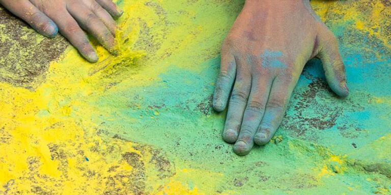 Hands making a colorful mural with vibrant chalk.