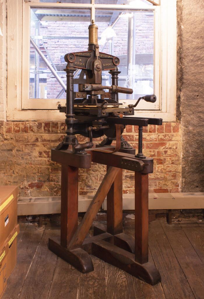 Photograph depicting an historic printing press inside an historic brick building.